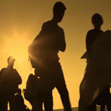 Silhouettes of people walking across a field